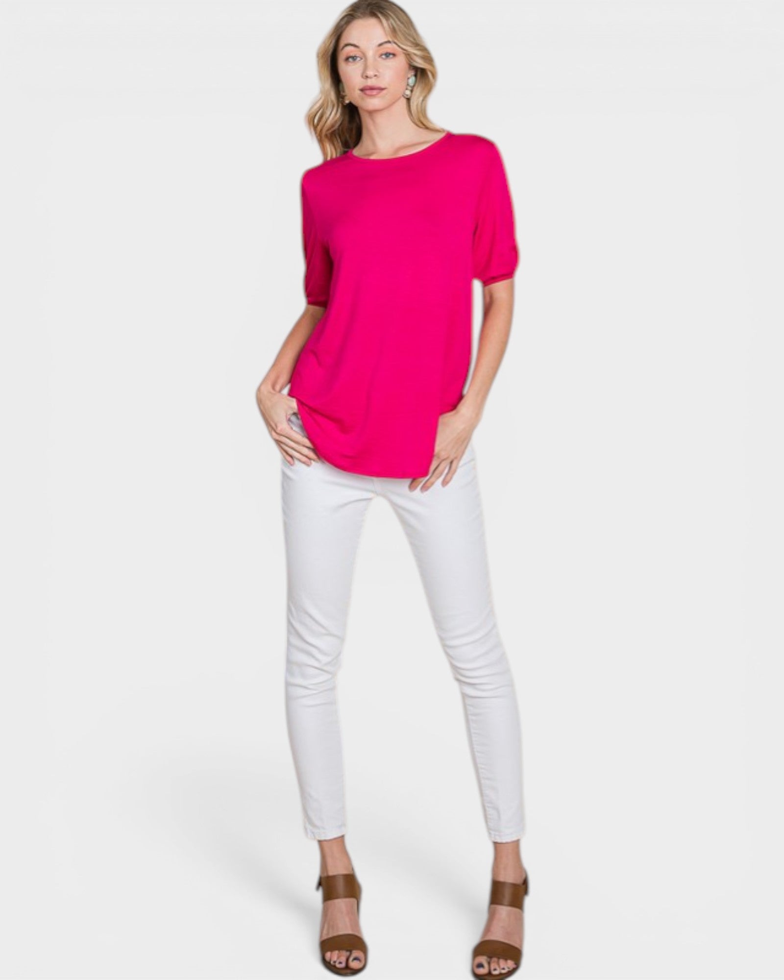 Woman wearing a bright pink top and white pants on a white background