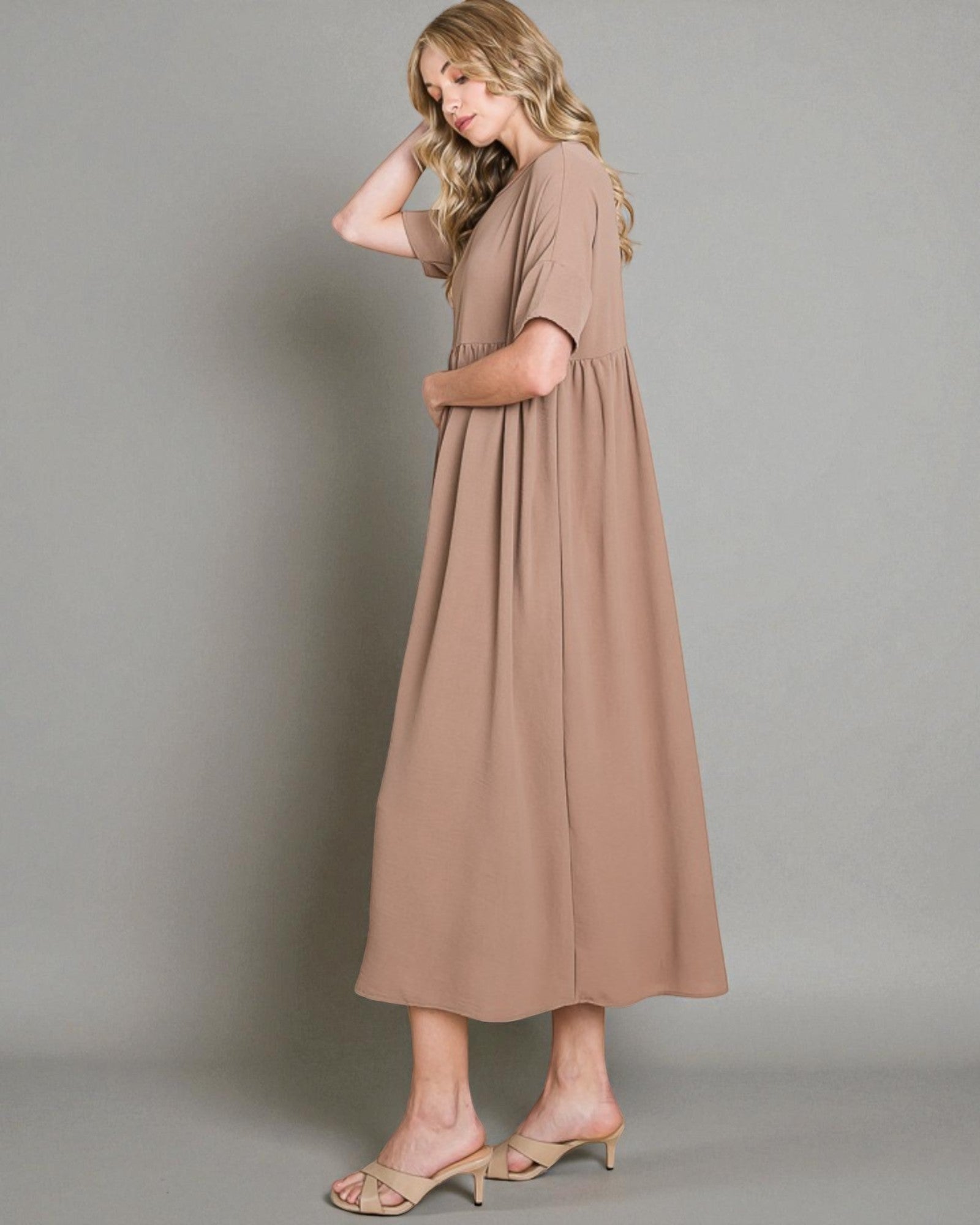 Woman wearing a long brown dress against a plain background