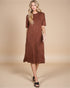 Woman wearing a brown patterned dress against a beige background