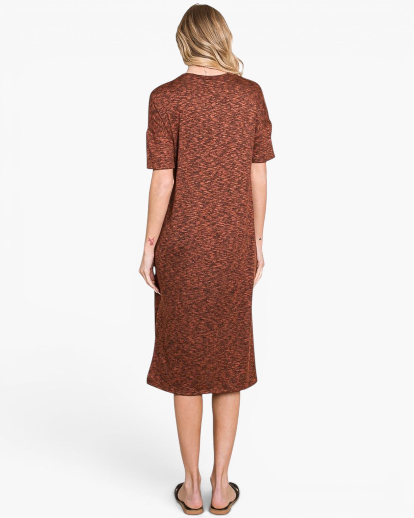 A woman viewed from the back wearing a short-sleeve, knee-length knit dress with a rust-brown and terracotta heathered pattern, paired with brown sandals, against a plain white studio background.
