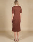 Woman wearing a brown dress against a beige background
