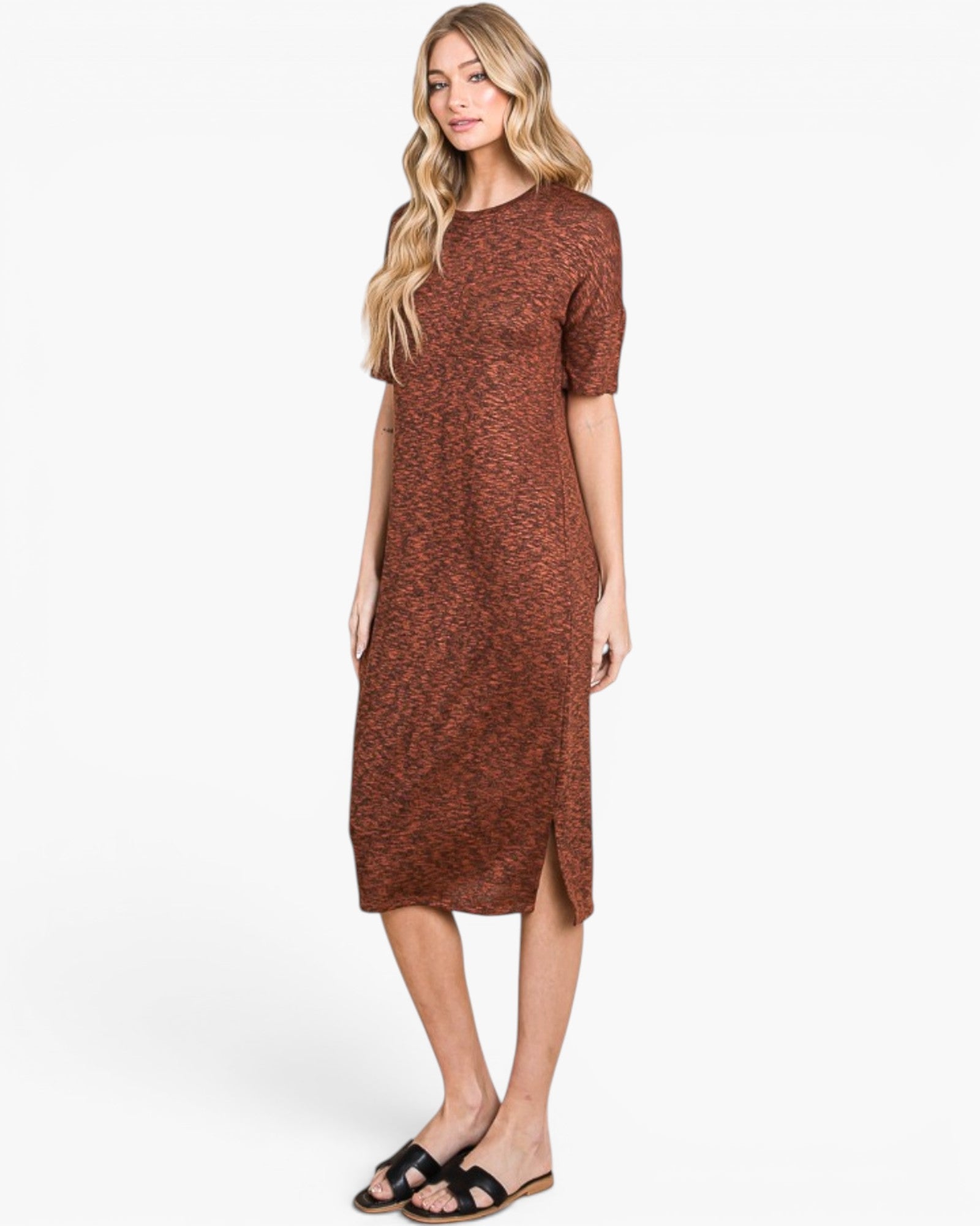 A woman modeling a short-sleeve, knee-length brown knit dress with a subtle heathered texture, paired with black slide sandals, against a plain white studio background.