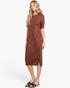 A woman modeling a short-sleeve, knee-length brown knit dress with a subtle heathered texture, paired with black slide sandals, against a plain white studio background.