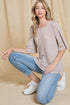 Woman wearing a beige sweater, blue jeans, and white sneakers on a beige background