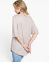 A woman wearing a light beige waffle-knit short-sleeve top, shown from a back-three-quarter view against a plain white background.
