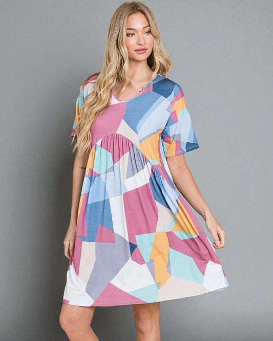 Woman wearing a colorful geometric patterned dress against a gray background