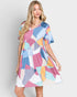 Woman wearing a colorful geometric patterned dress on a plain background