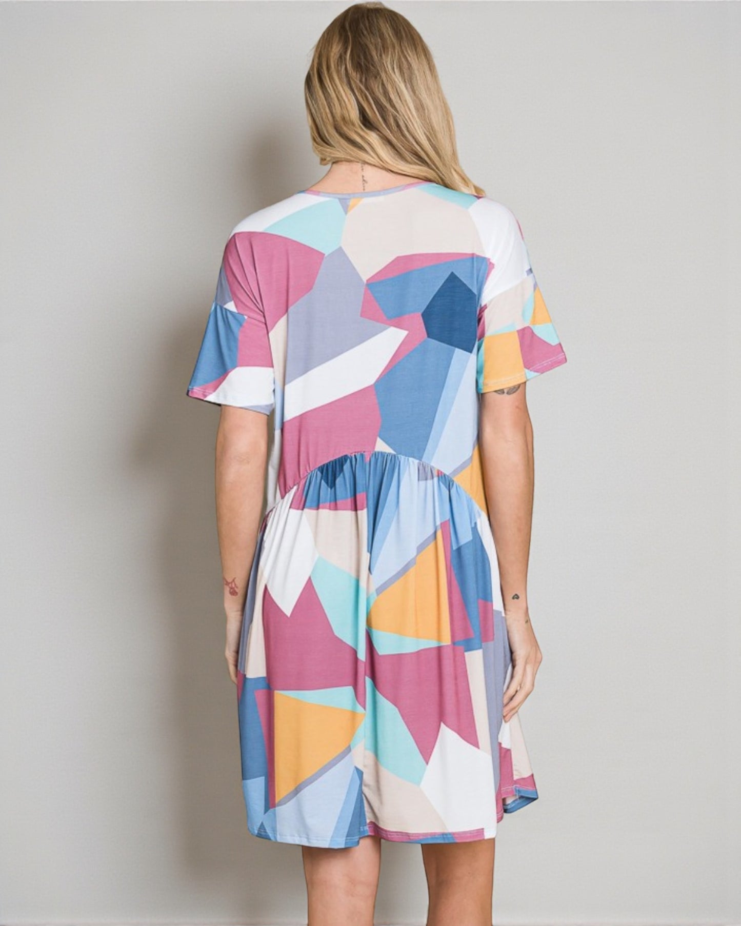 Woman wearing a colorful geometric patterned dress against a plain background