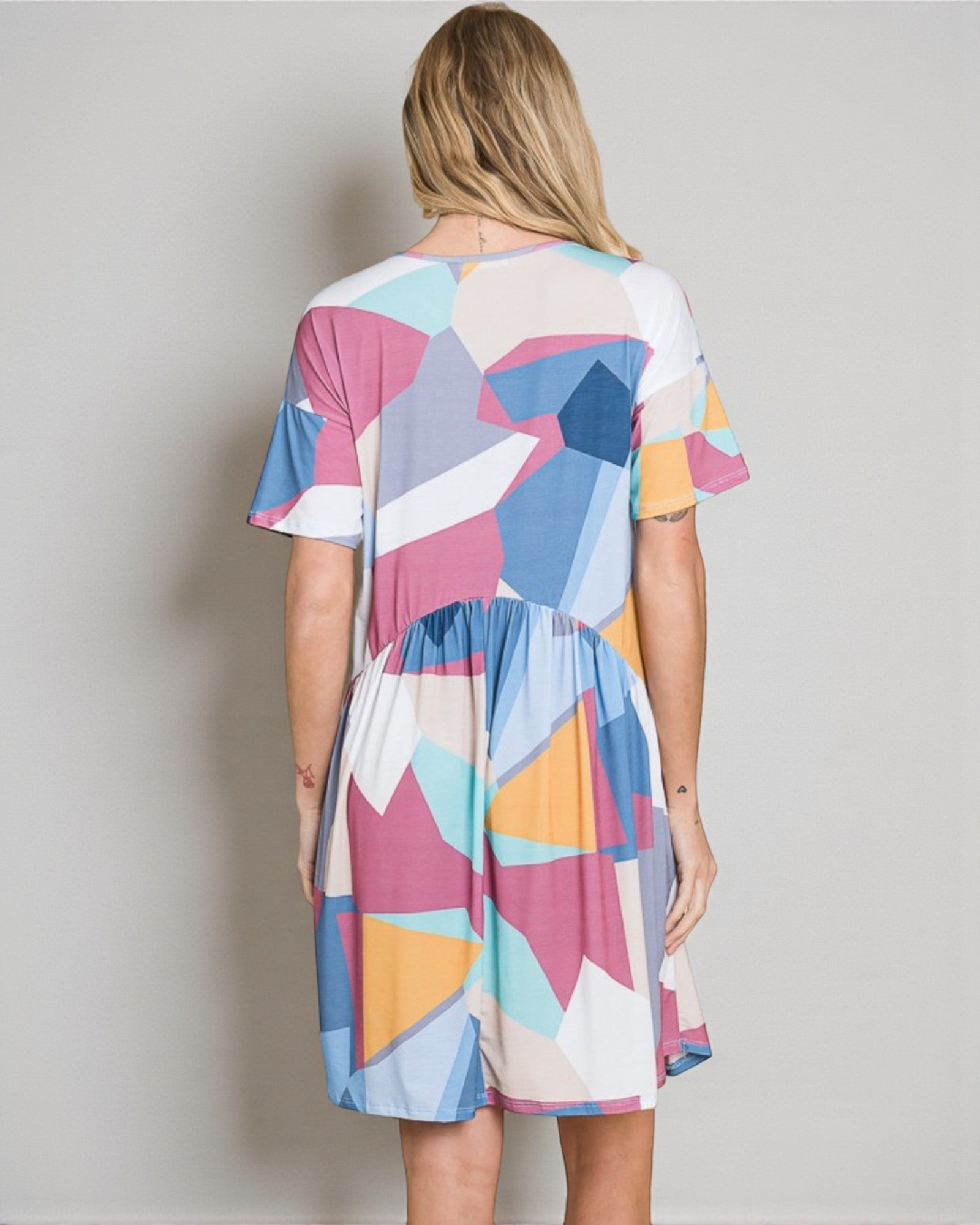 Woman wearing a colorful geometric patterned dress against a plain background