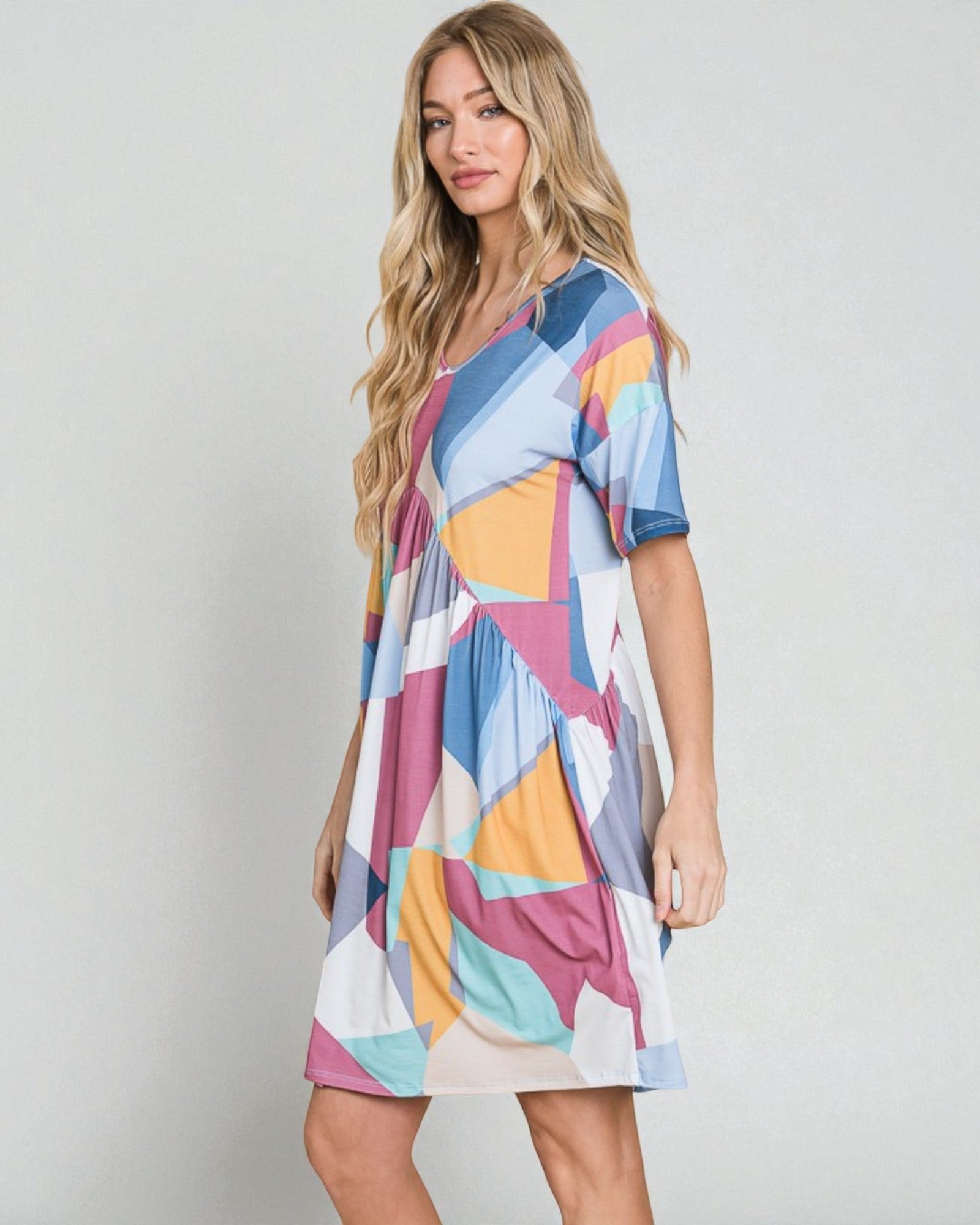 Woman wearing a colorful patterned dress on a plain background