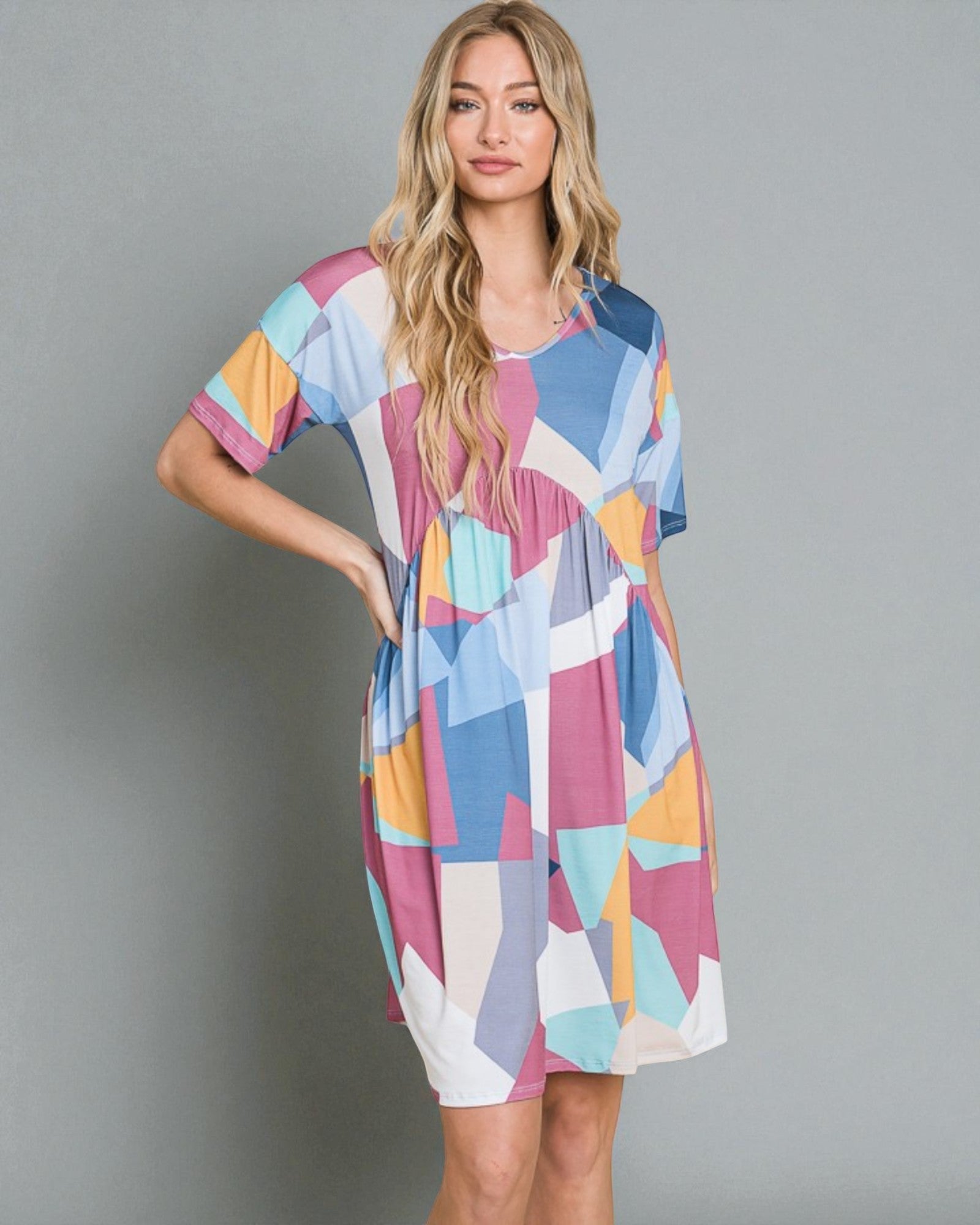Woman wearing a colorful geometric patterned dress against a gray background