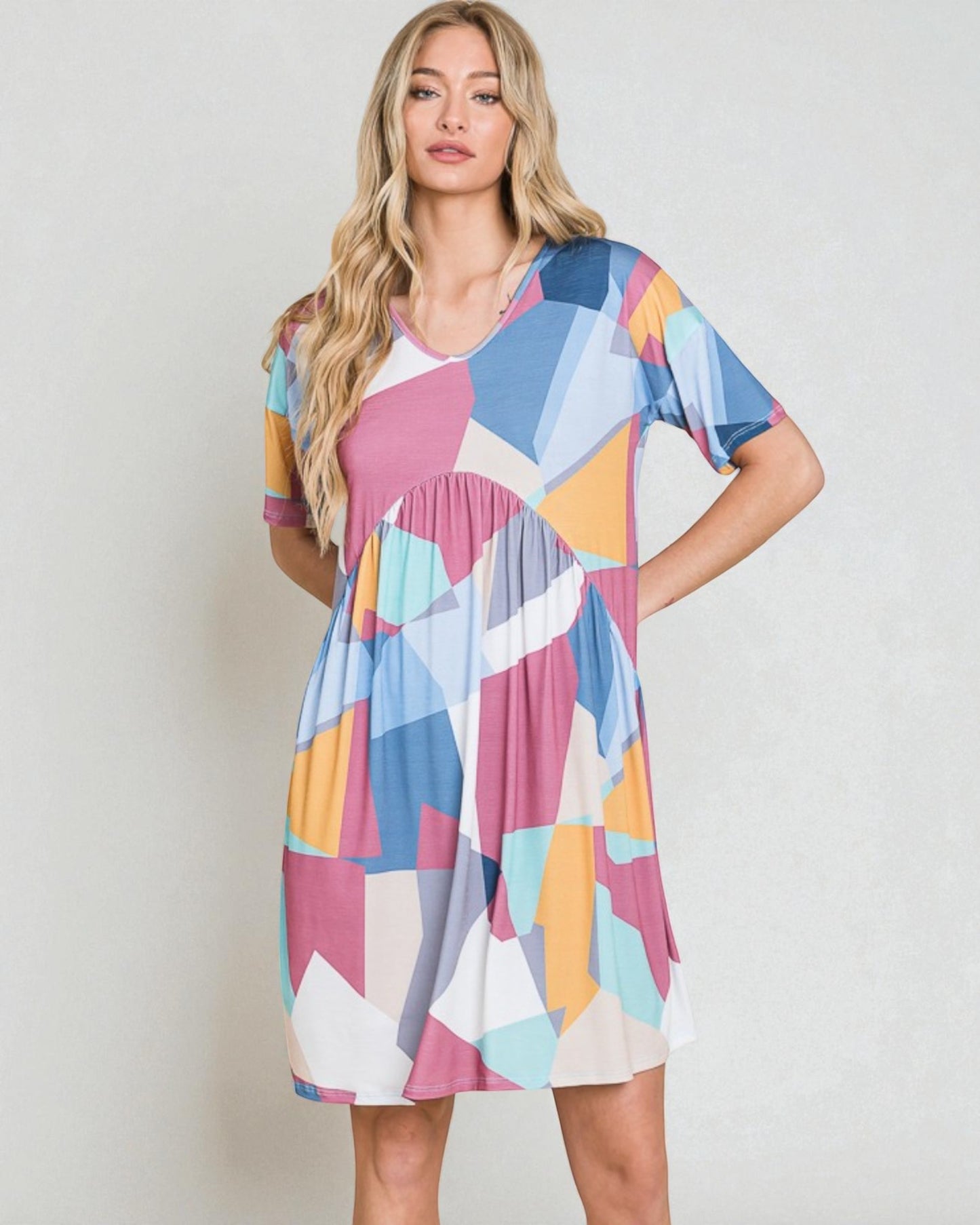 Woman wearing a colorful geometric patterned dress against a plain background