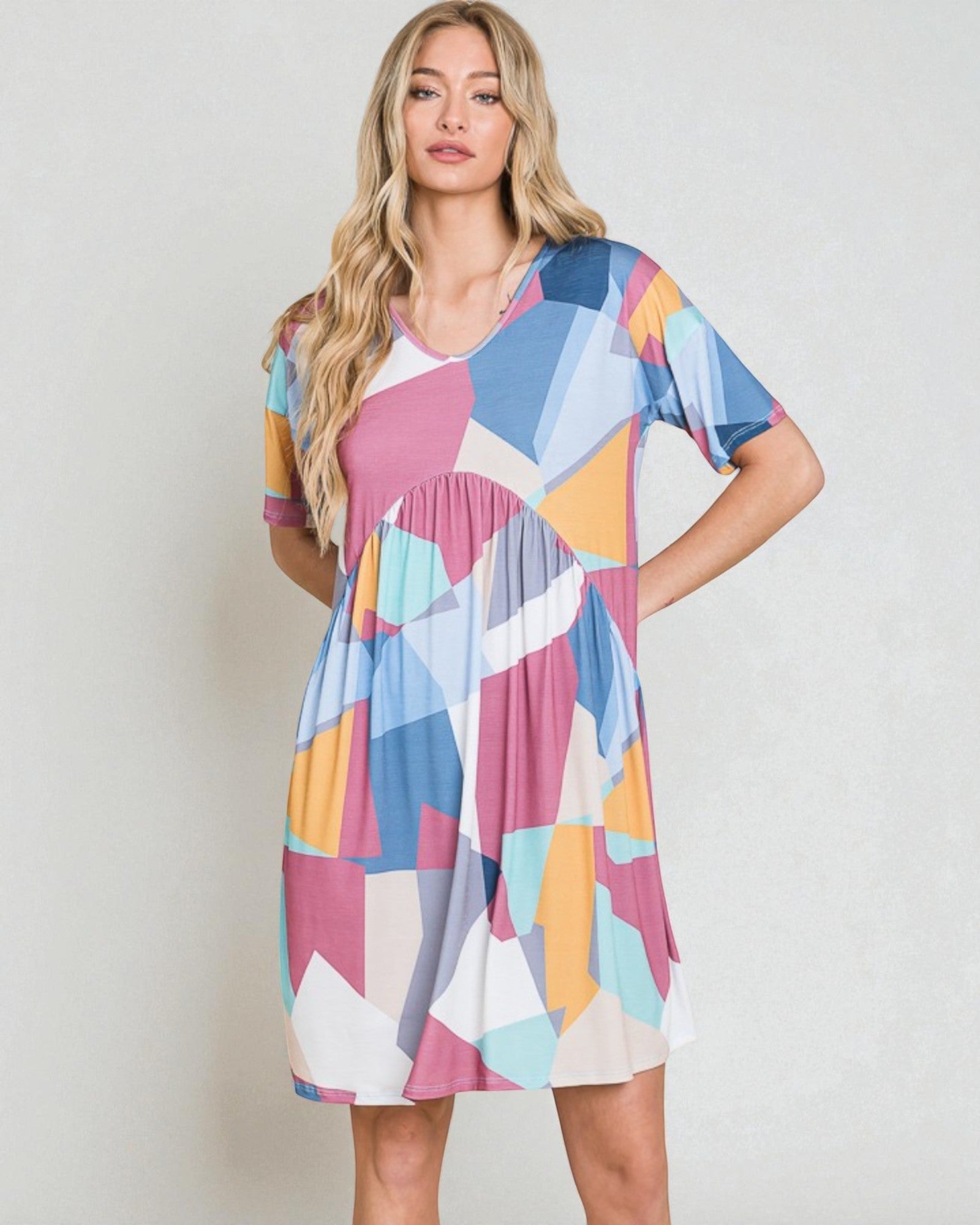 Woman wearing a colorful geometric patterned dress against a plain background