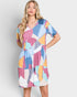 Woman wearing a colorful geometric patterned dress on a plain background