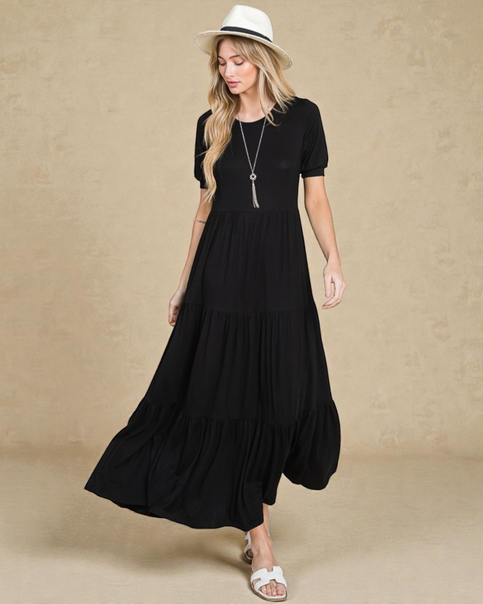 Woman wearing a black dress and white hat on a beige background