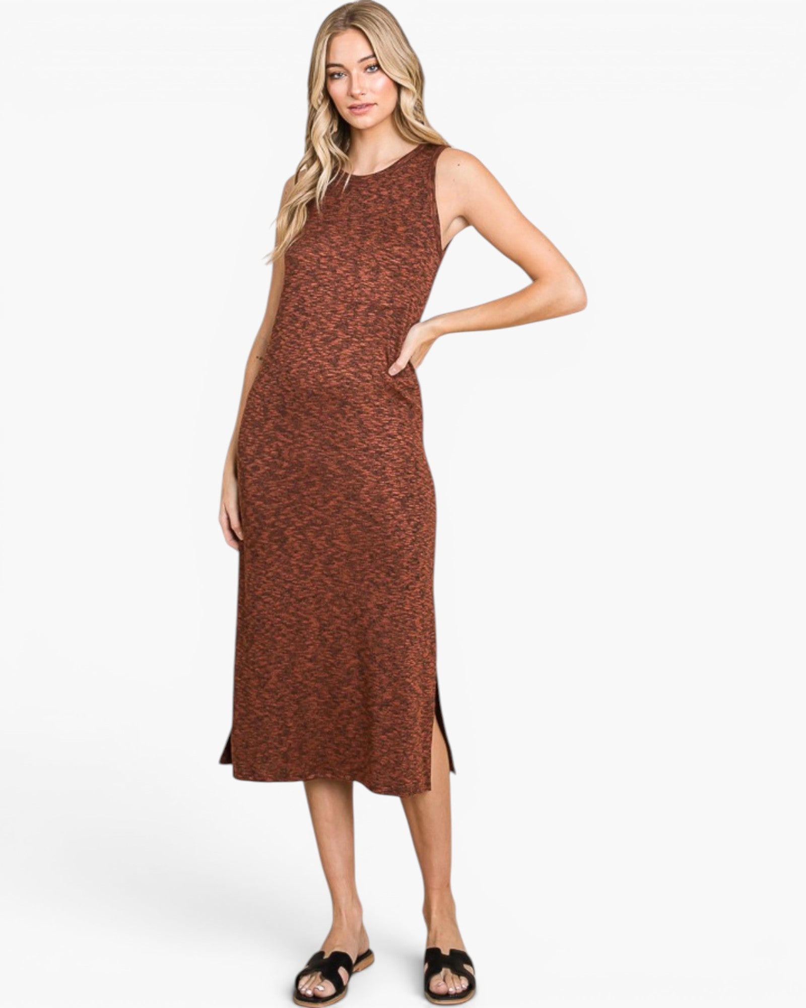 A woman modeling a sleeveless, knee-length rust-brown knit dress with a subtle speckled texture and side slits, paired with black slide sandals, against a plain white studio background.