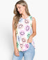 A woman wearing a sleeveless white top with a colorful smiley face pattern, paired with light blue jeans, against a plain white background.