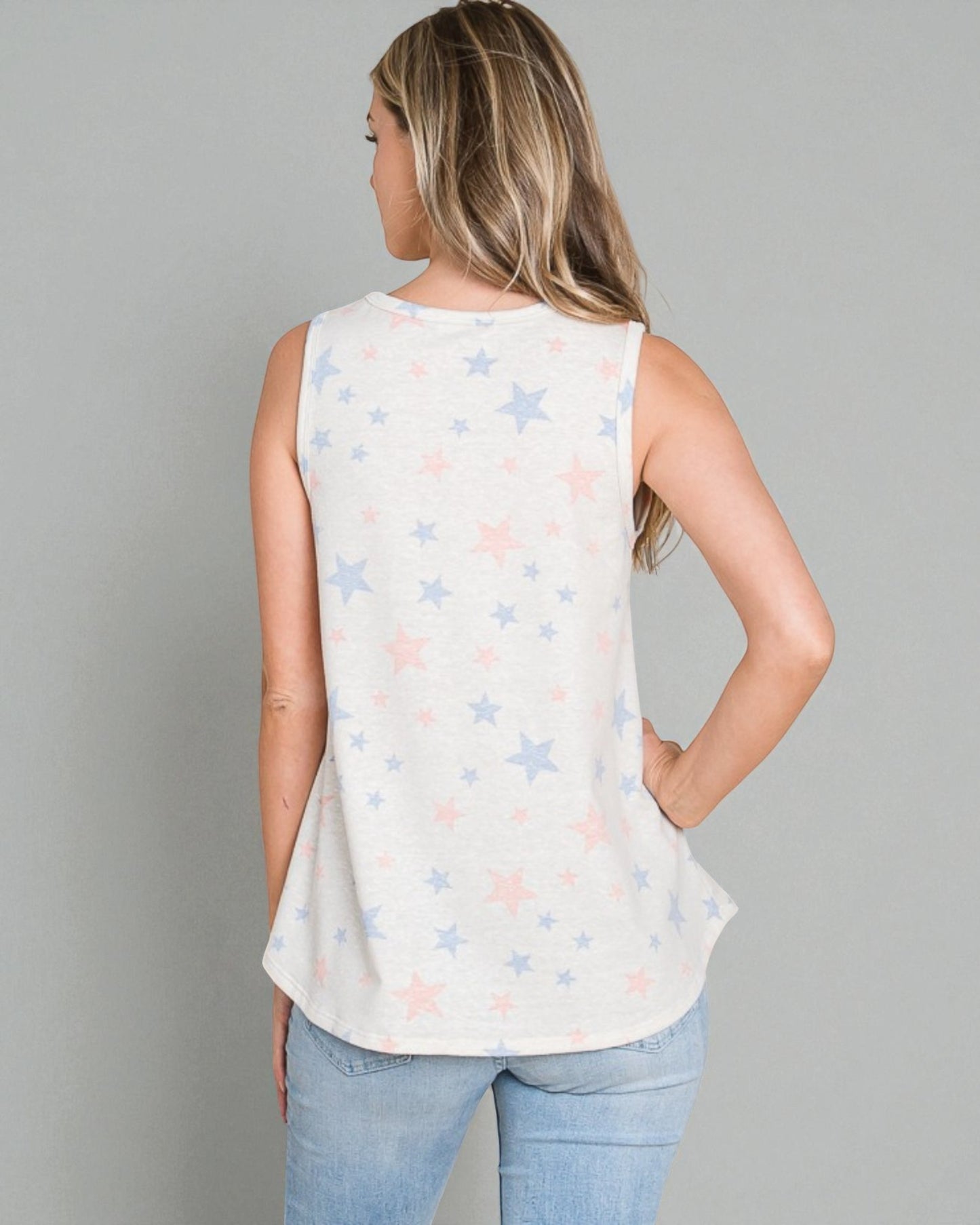 Woman wearing a sleeveless top with star pattern against a gray background