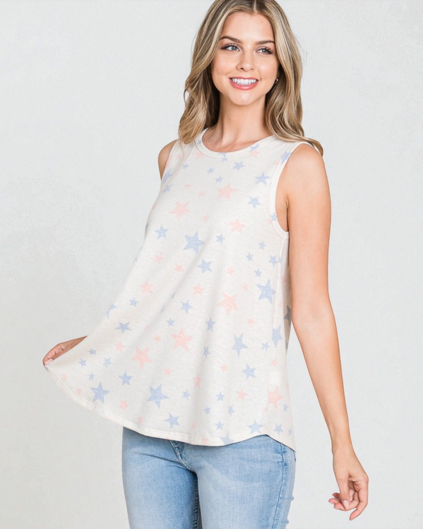 Woman wearing a sleeveless top with star pattern and jeans on a white background