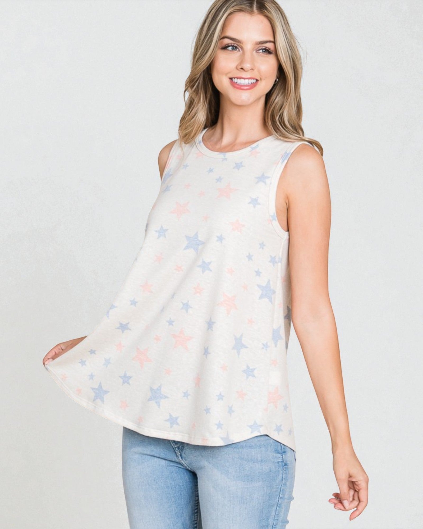 Woman wearing a sleeveless top with star pattern and jeans on a white background