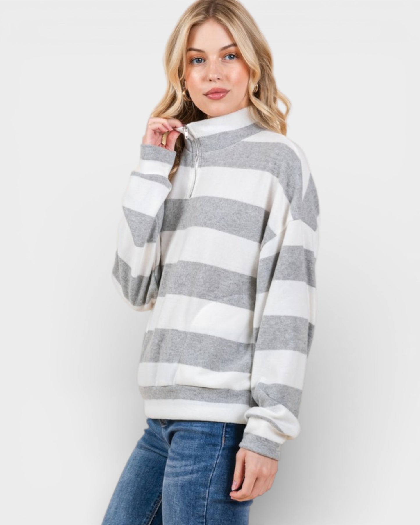 Woman wearing a gray and white striped sweater on a plain background