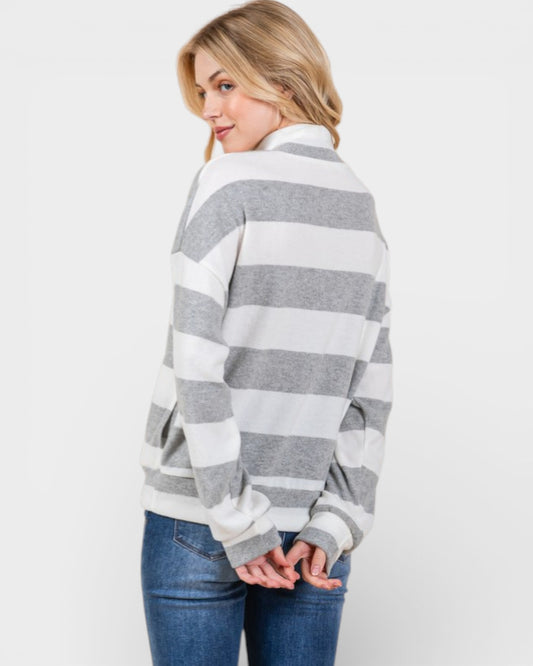 Woman wearing a gray and white striped sweater on a plain background
