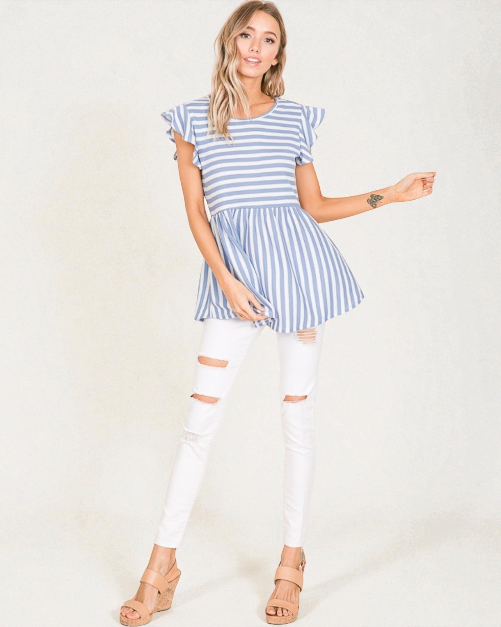 Woman wearing a blue and white striped dress with white pants on a plain background