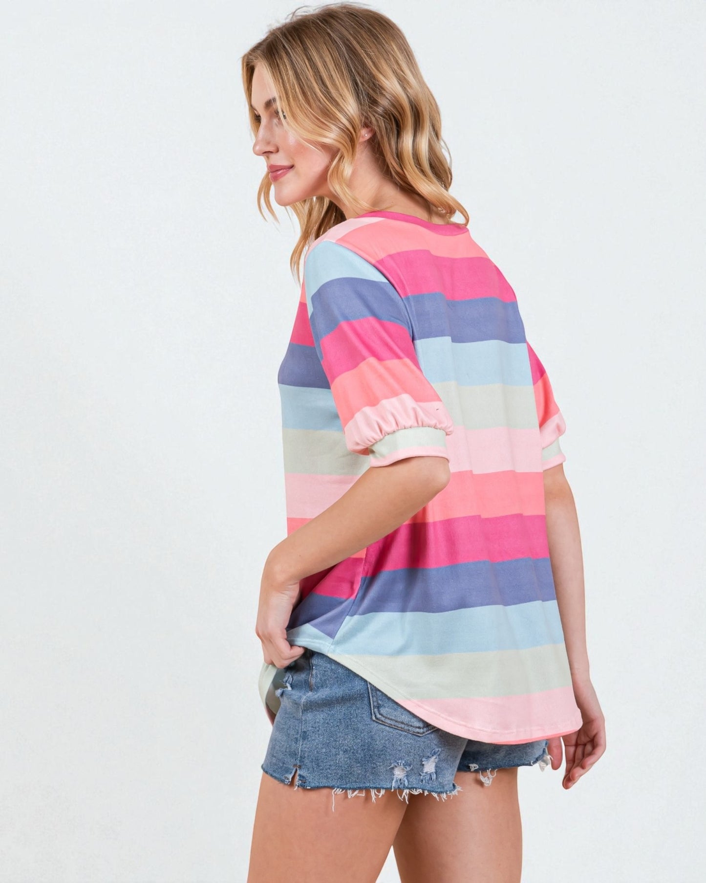 Woman wearing a colorful striped shirt and denim shorts on a white background