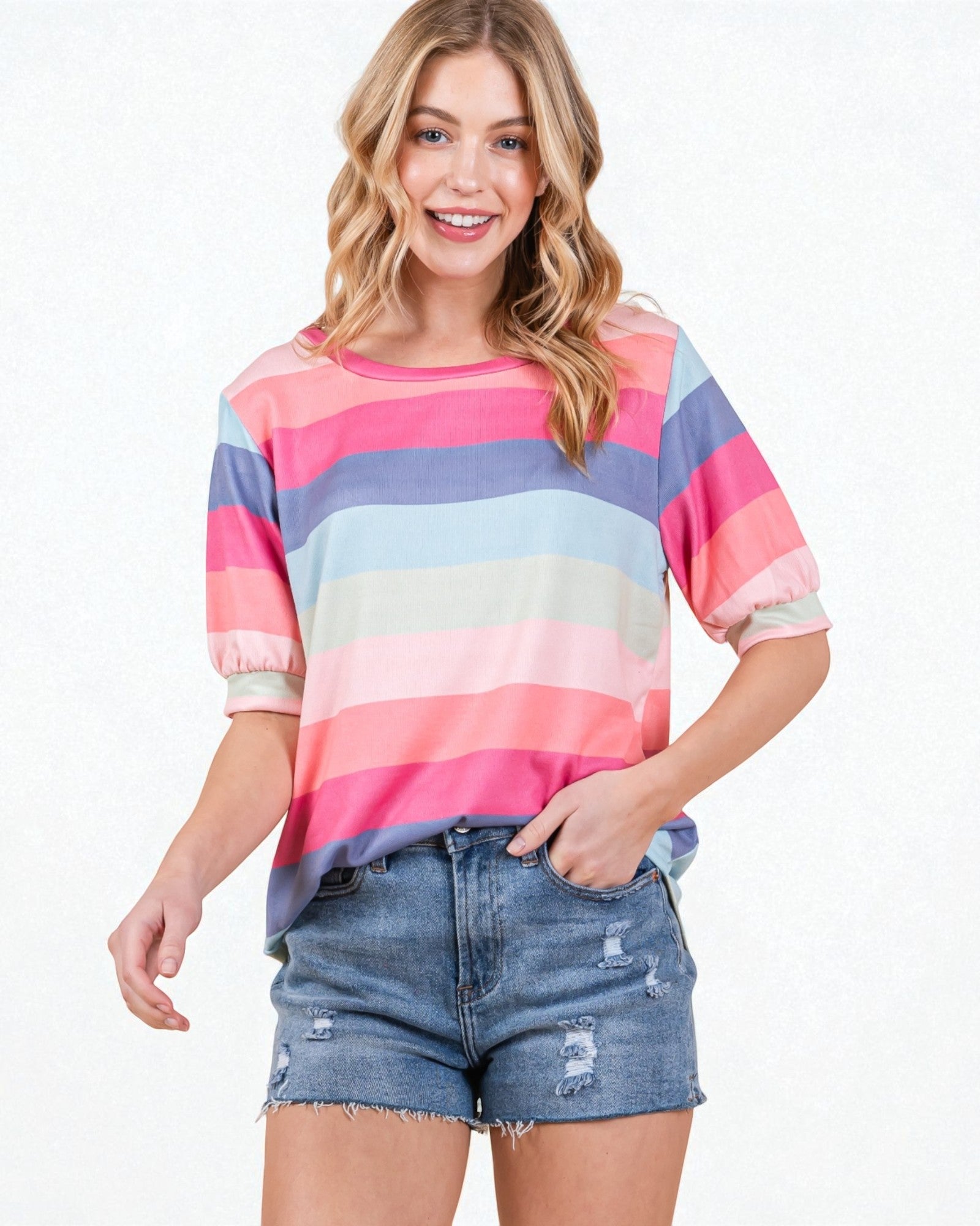 Woman wearing a colorful striped shirt and denim shorts on a white background