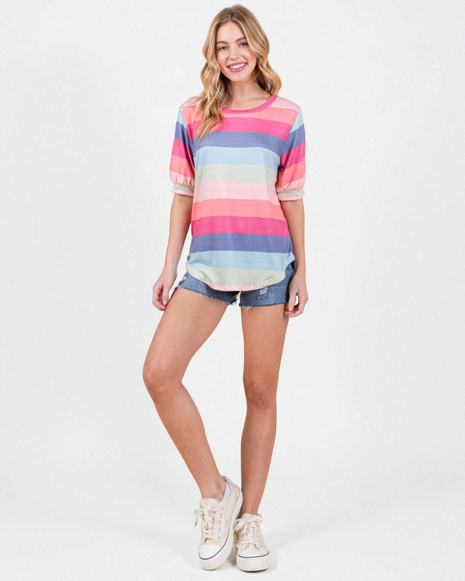 Woman wearing a colorful striped shirt and denim shorts on a white background