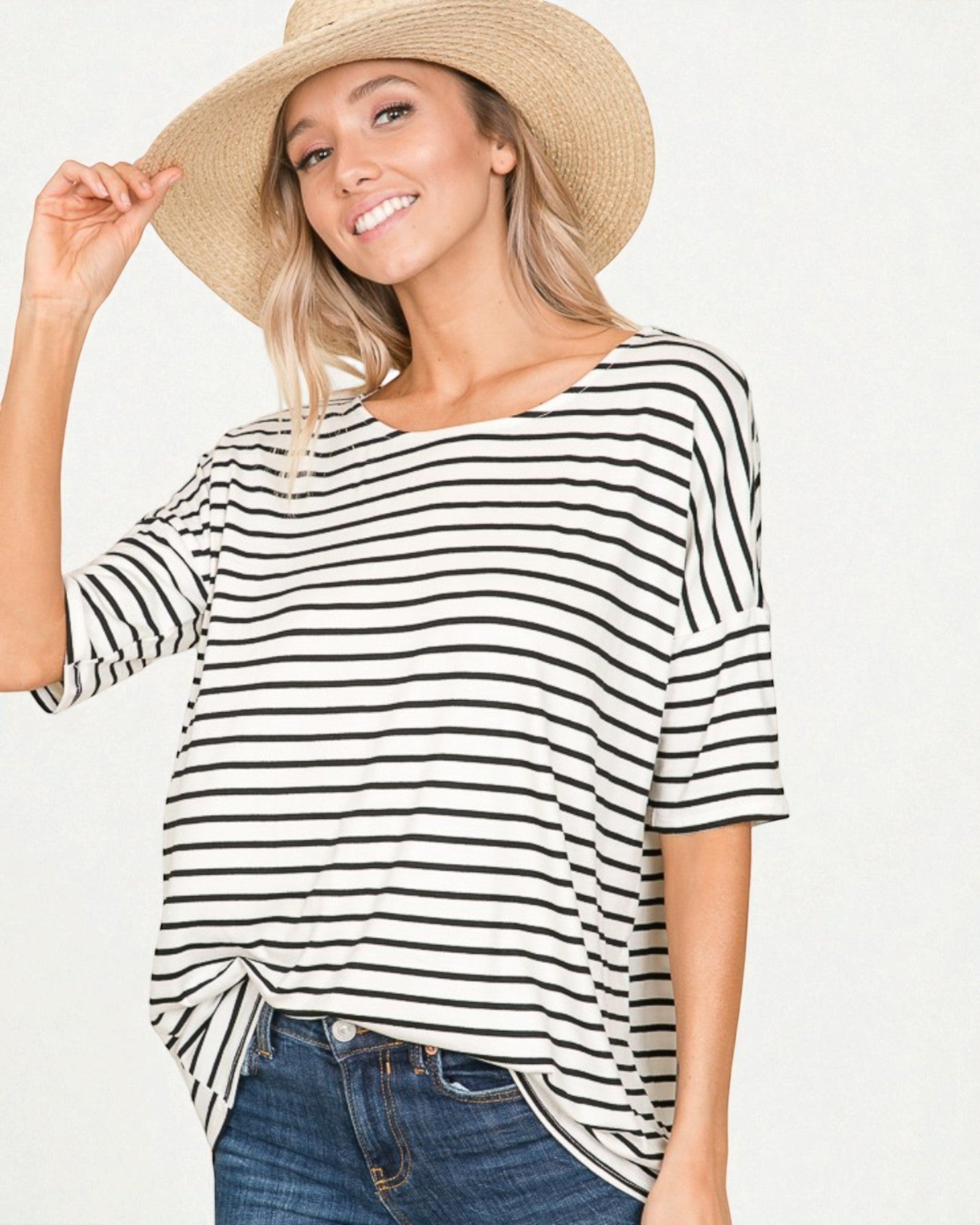 Woman wearing a black and white striped shirt with a wide-brimmed hat on a plain background