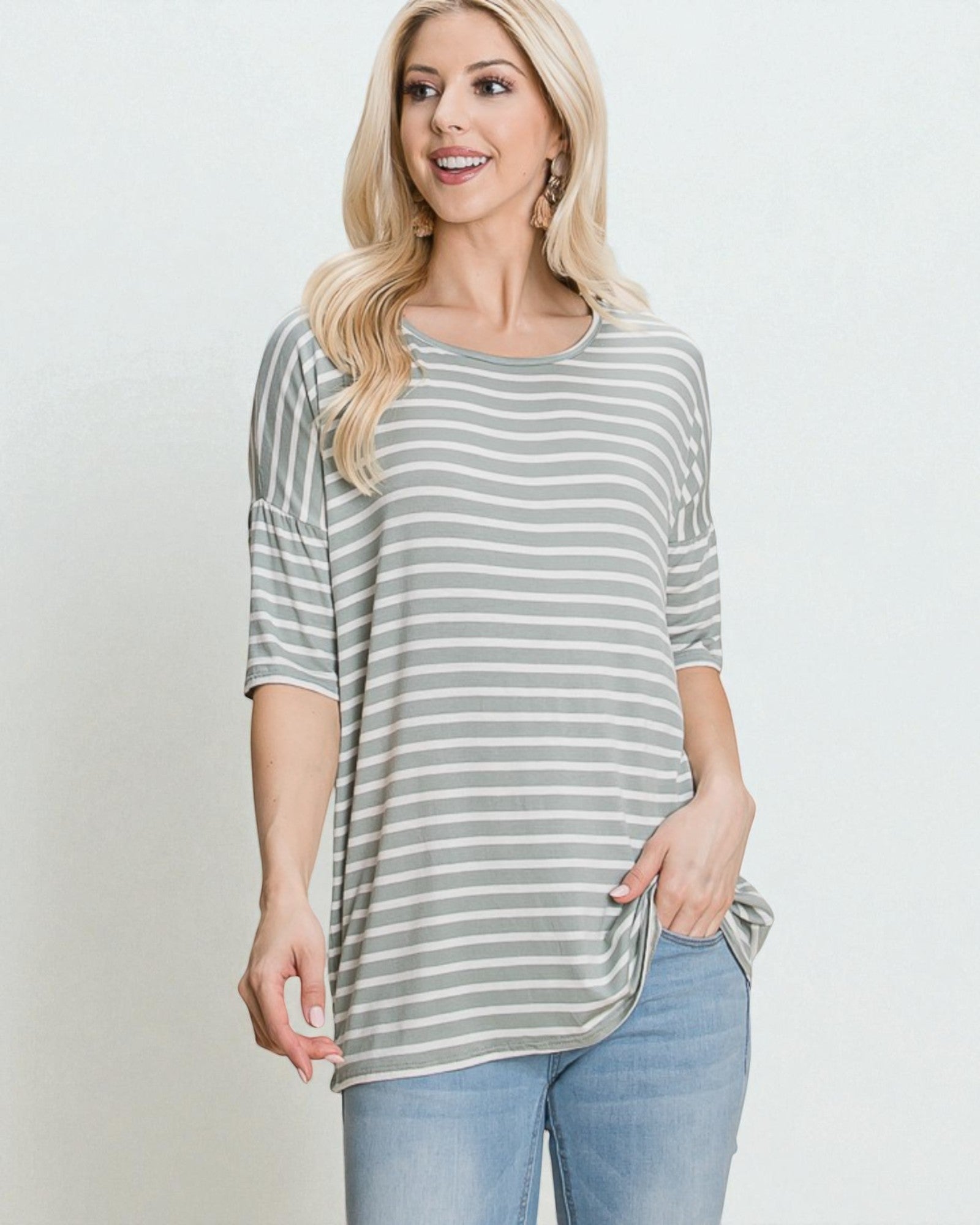 Woman wearing a gray and white striped shirt with a plain background