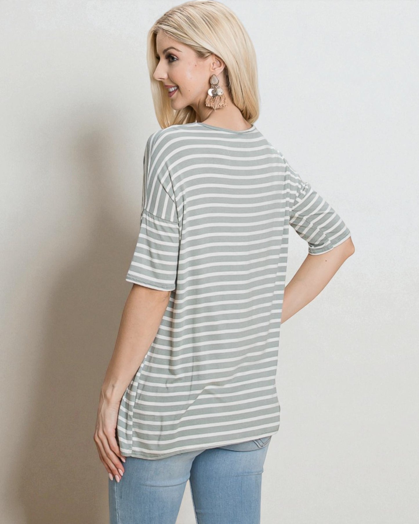 Woman wearing a striped shirt and jeans against a plain background