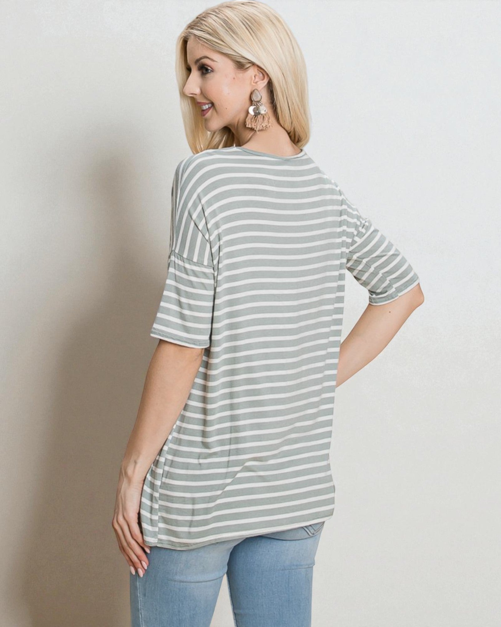 Woman wearing a striped shirt and jeans against a plain background