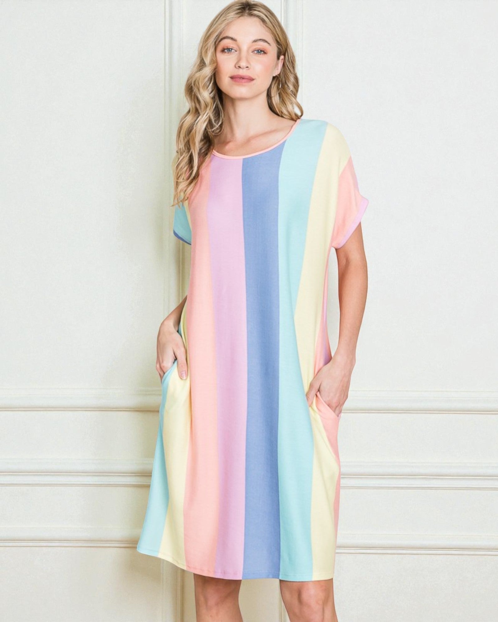 Woman wearing a pastel striped dress against a white wall