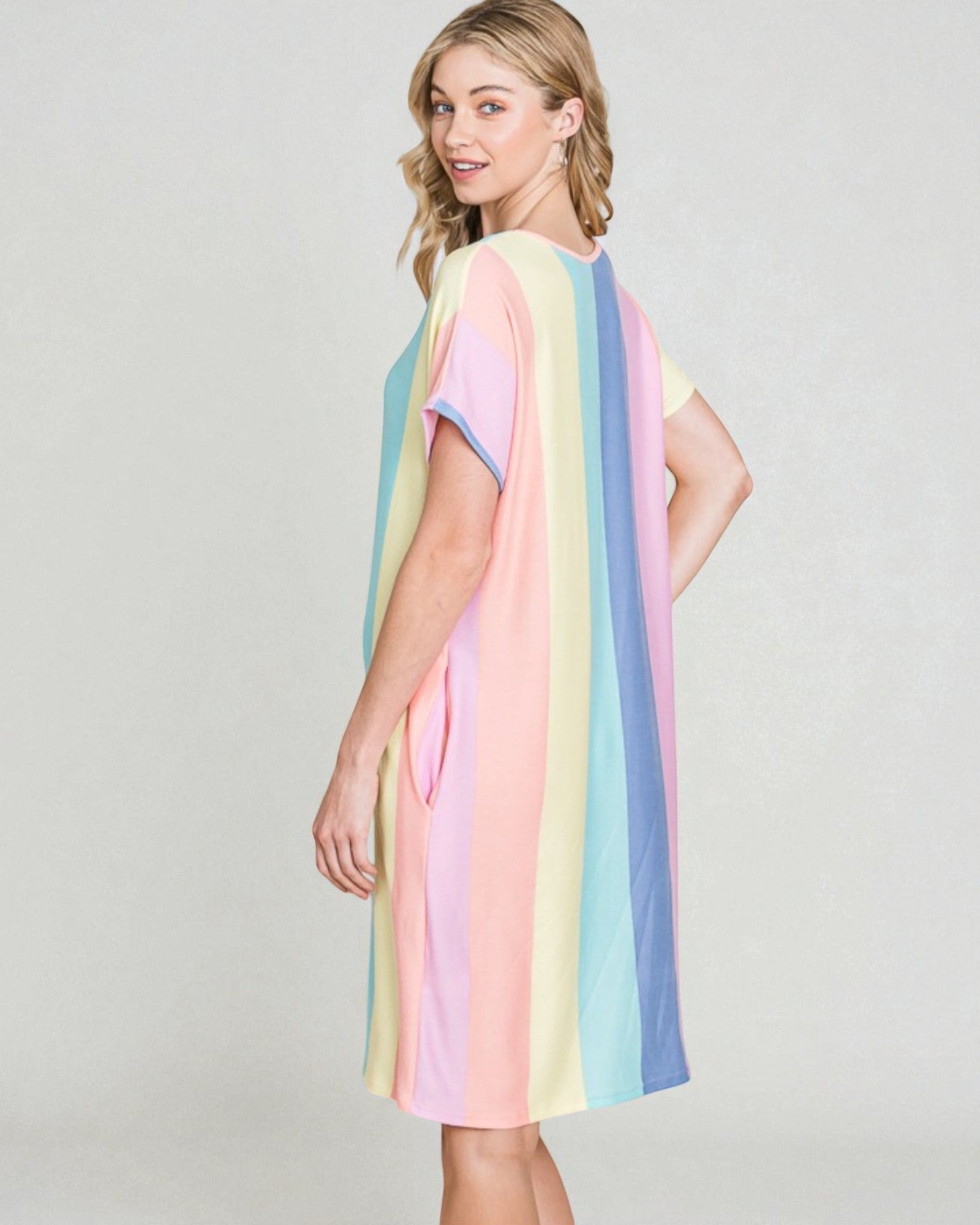 Woman wearing a pastel striped dress on a plain background