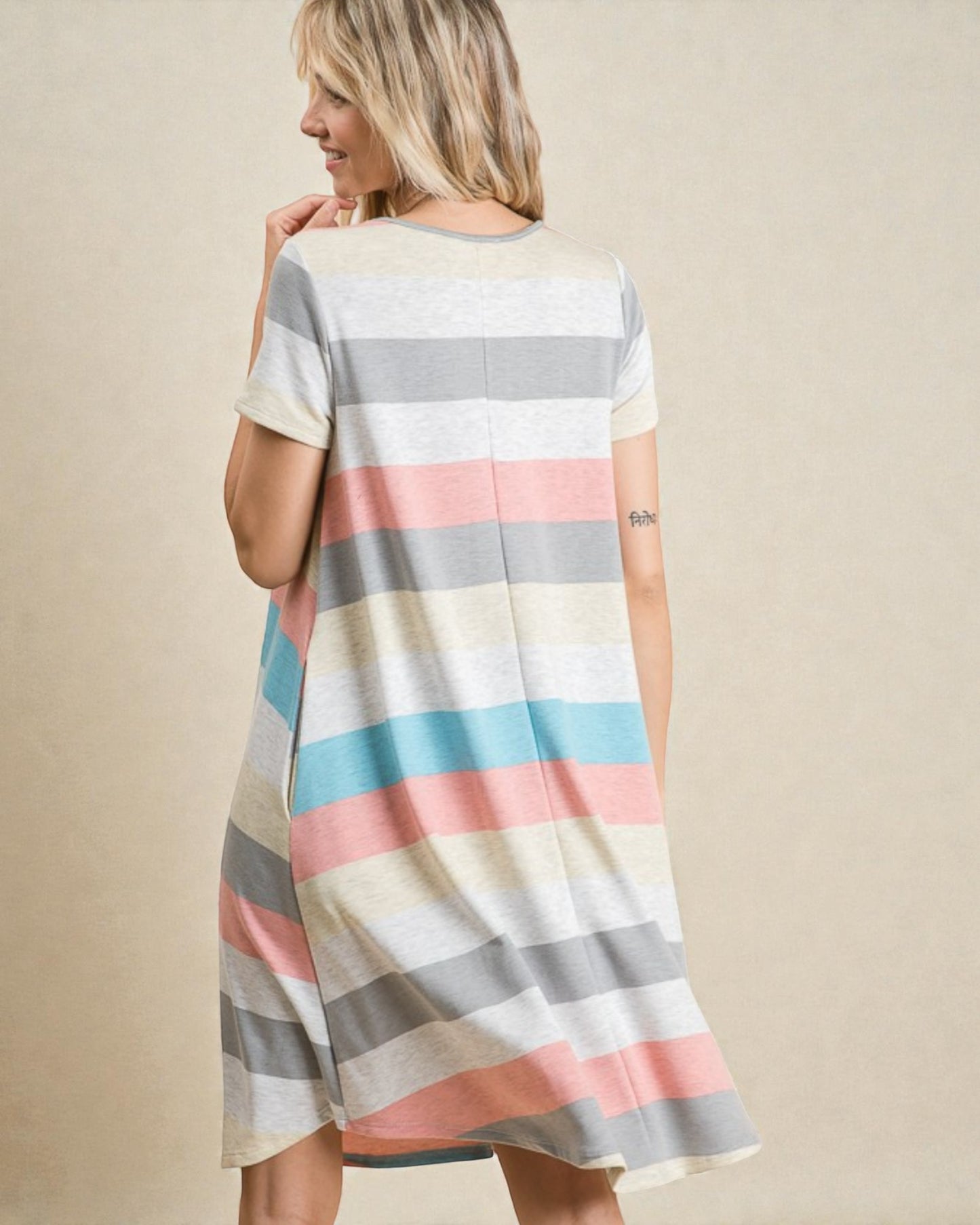 Woman wearing a striped dress with pastel colors on a beige background