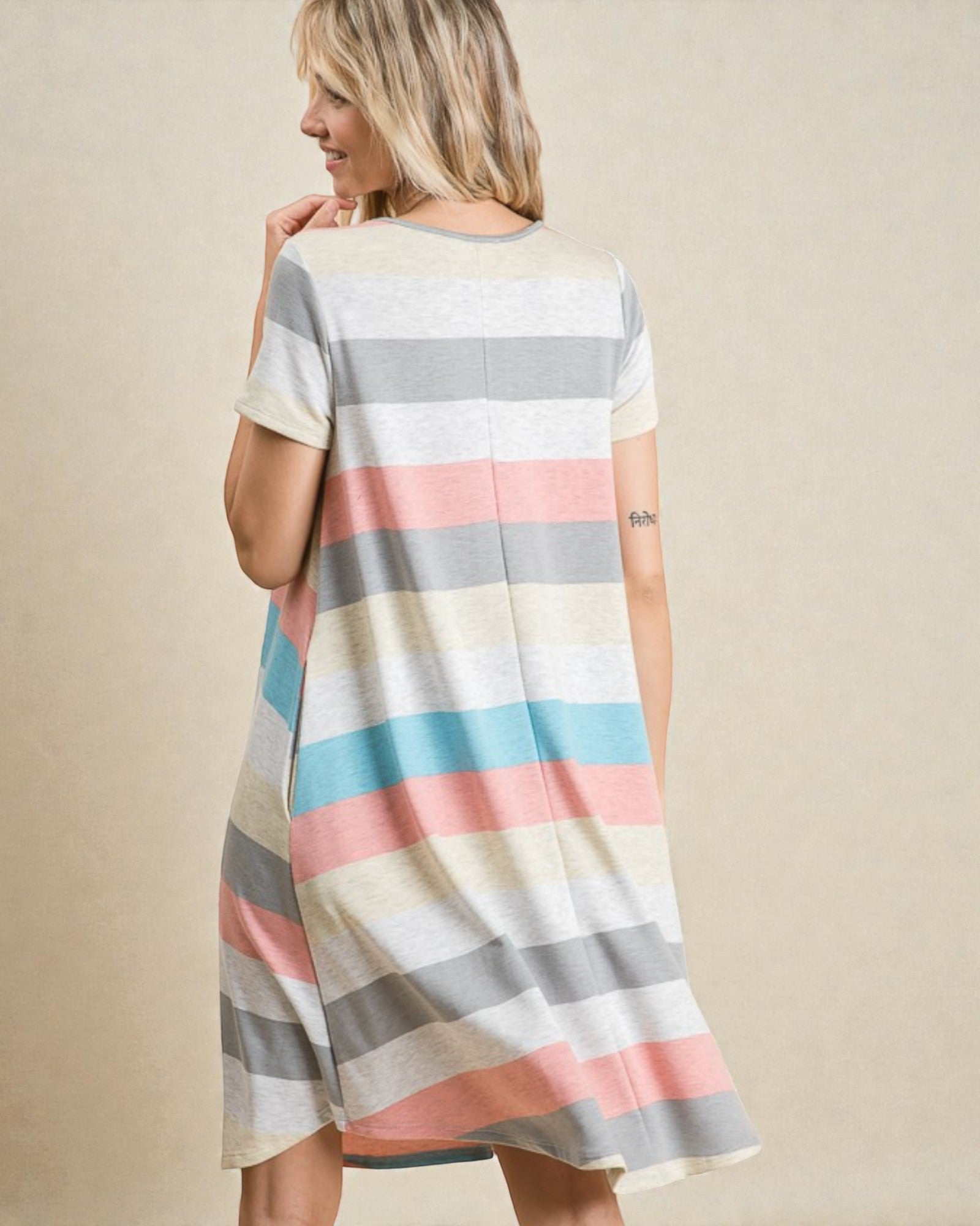 Woman wearing a striped dress with pastel colors on a beige background