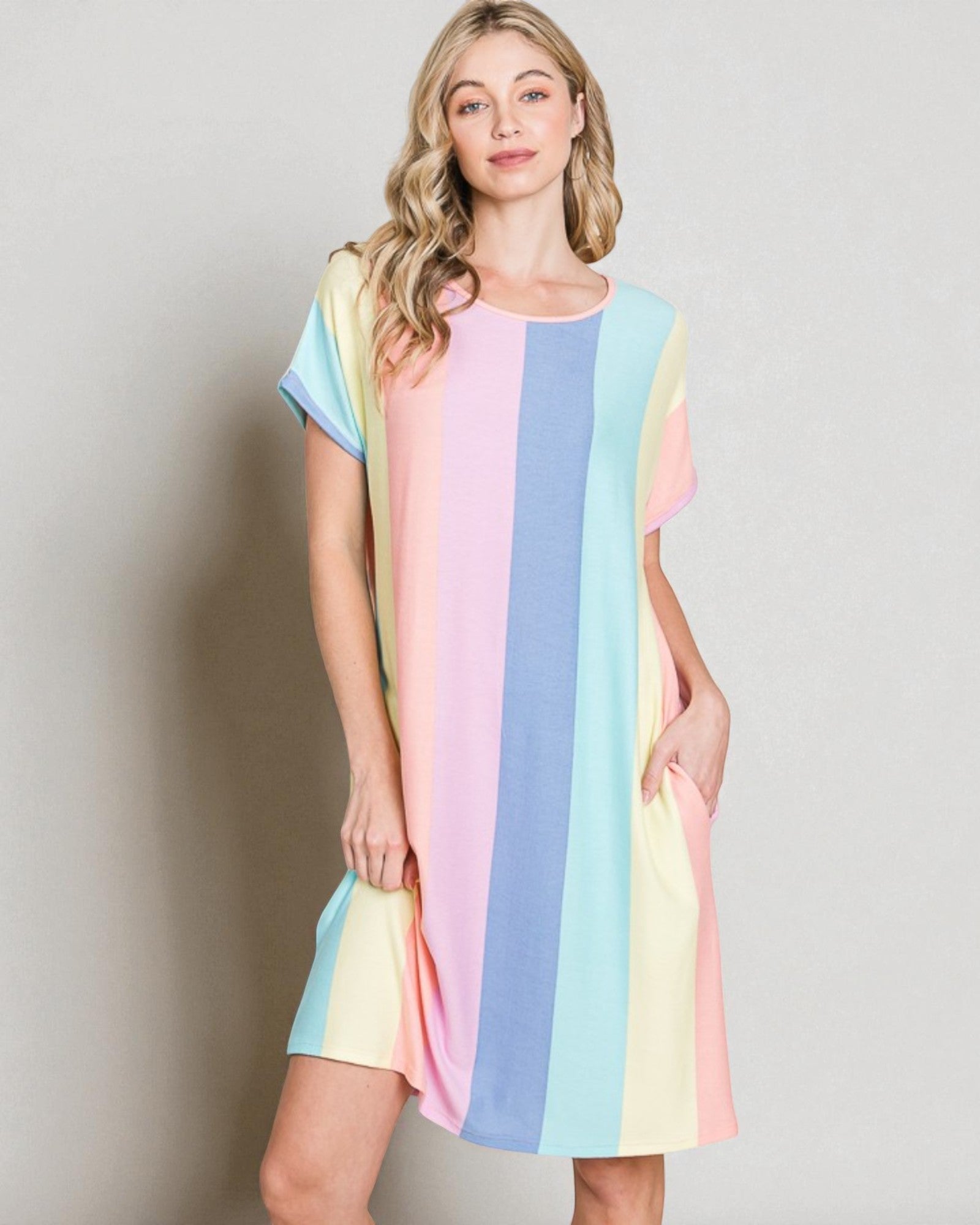 Woman wearing a pastel striped dress against a plain background