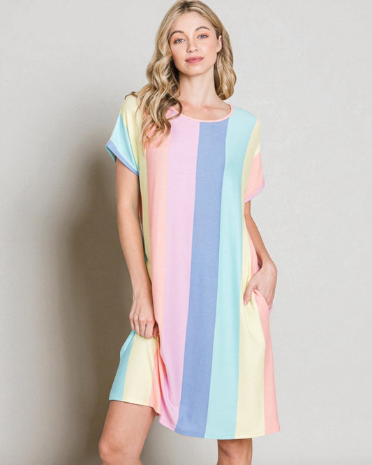 Woman wearing a pastel striped dress against a plain background