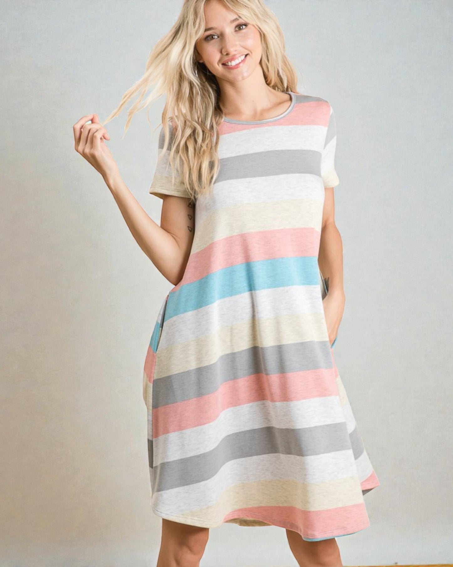 Woman wearing a colorful striped dress against a plain background