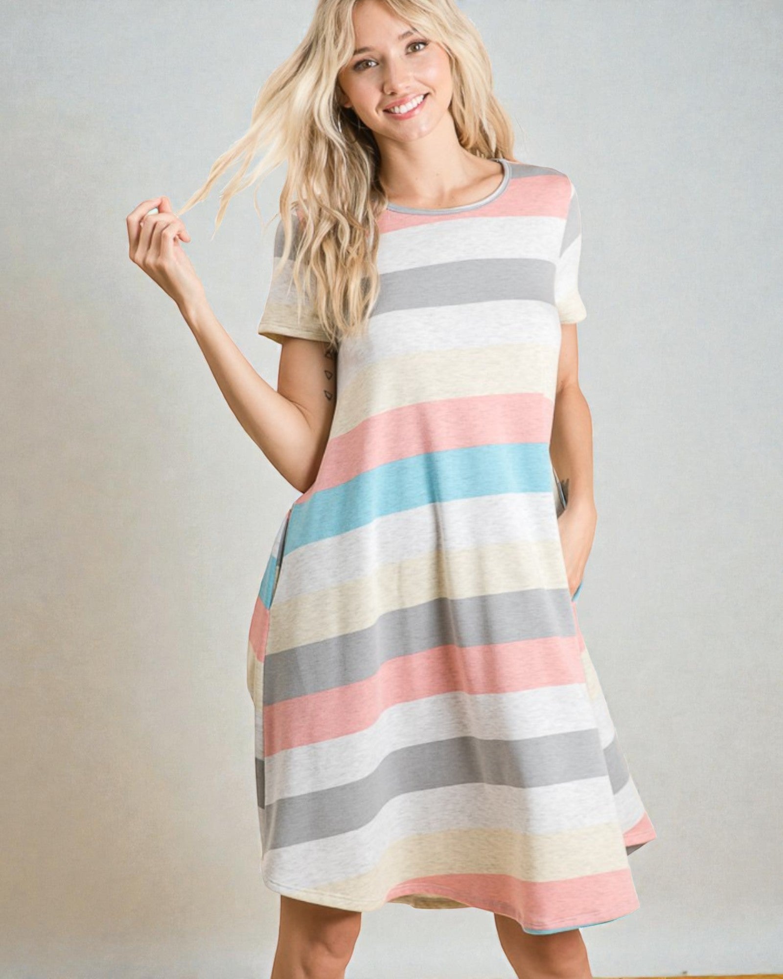 Woman wearing a colorful striped dress against a plain background