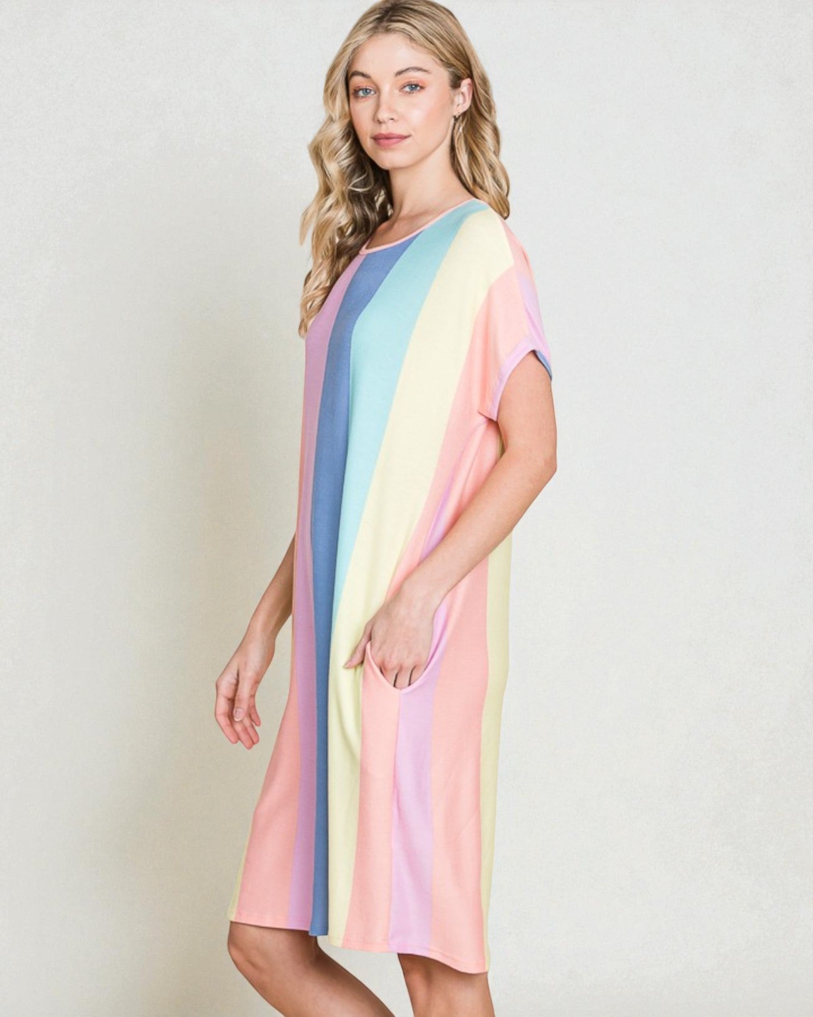 Woman wearing a pastel striped dress on a plain background