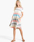A woman modeling a short-sleeve, knee-length A-line dress with horizontal pastel stripes in pink, blue, gray, beige, and white, set against a plain white studio background.