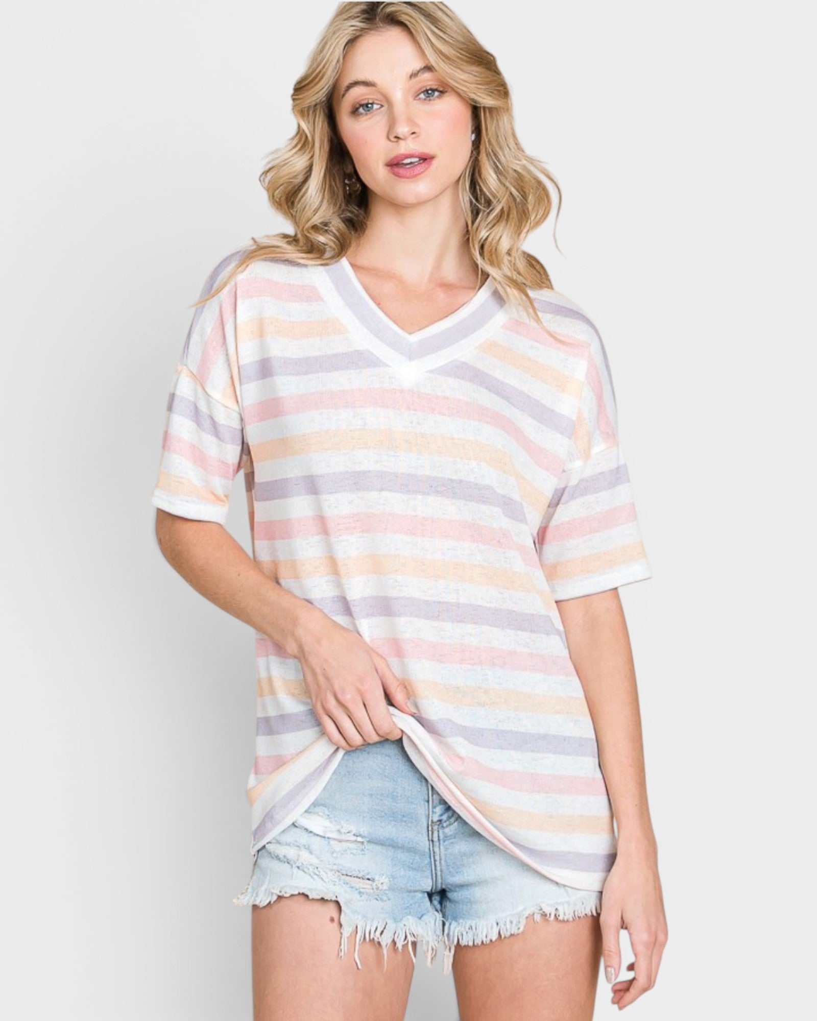 Woman wearing a striped shirt and denim shorts on a plain background