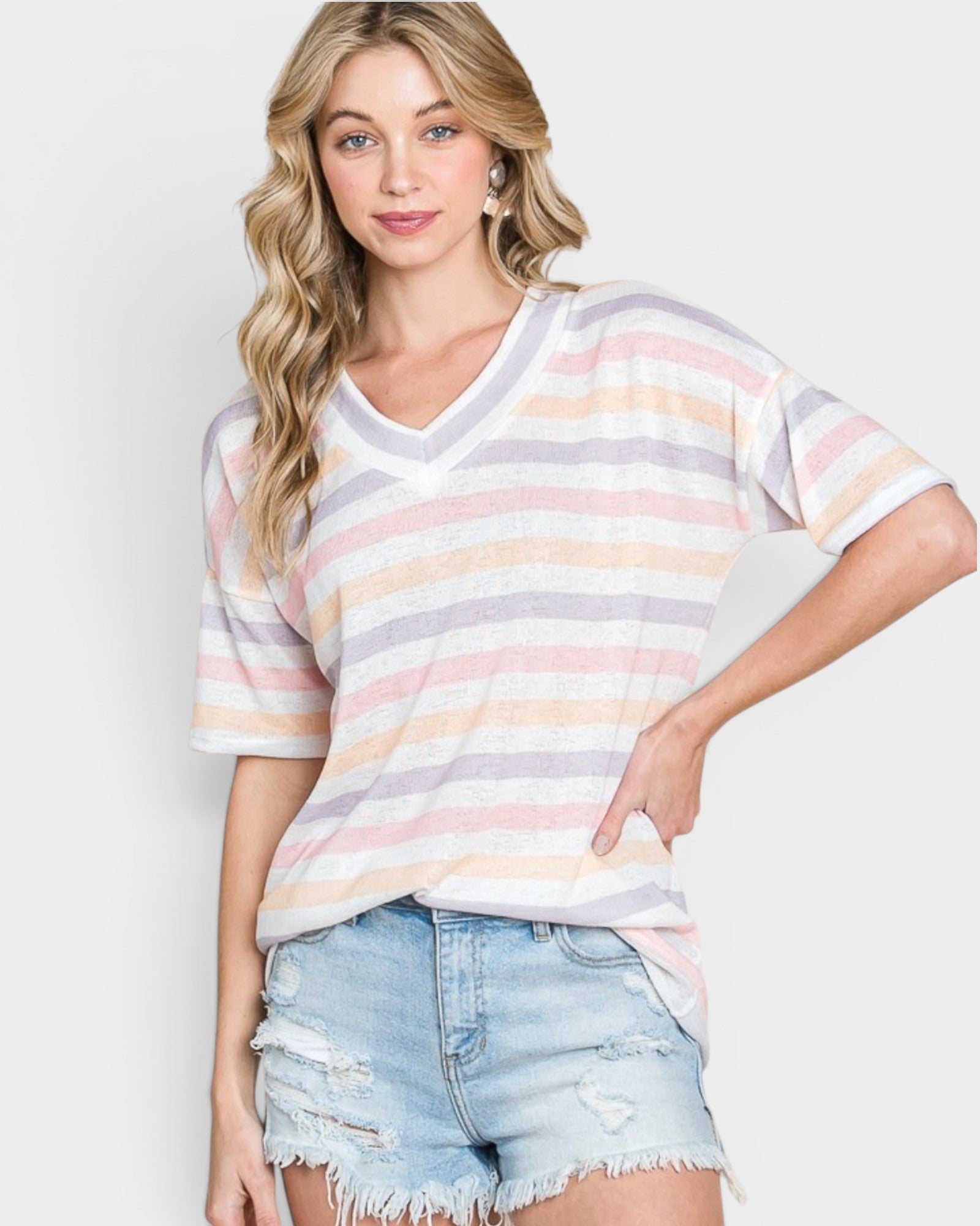 Woman wearing a striped shirt and denim shorts on a plain background