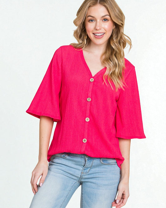Woman wearing a bright pink blouse with button details on a plain background