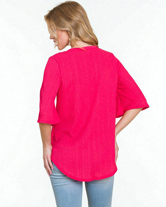 Woman wearing a bright pink shirt and light blue jeans on a white background