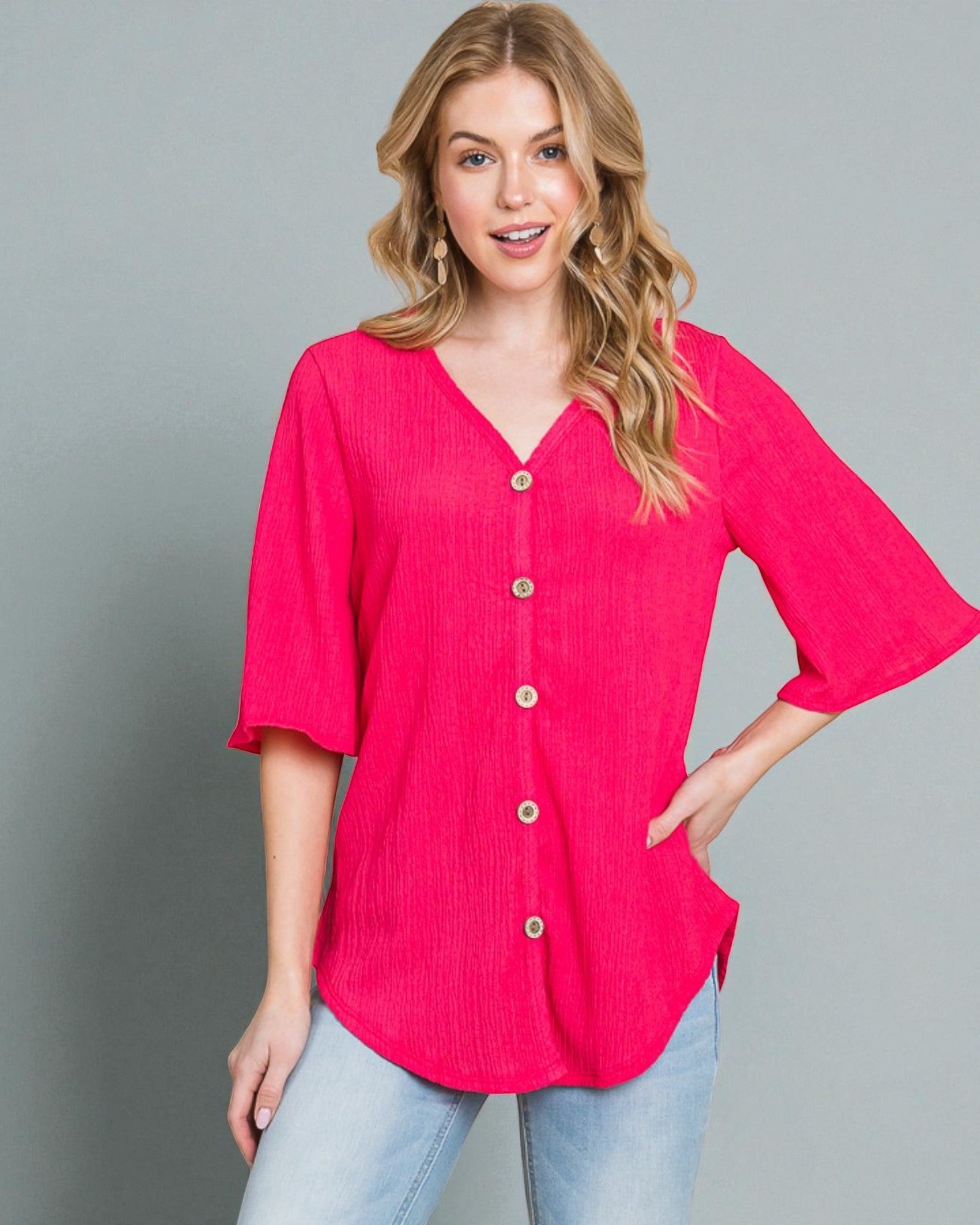 Woman wearing a bright pink button-up shirt against a gray background
