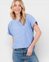 Woman wearing a blue patterned top and jeans on a white background